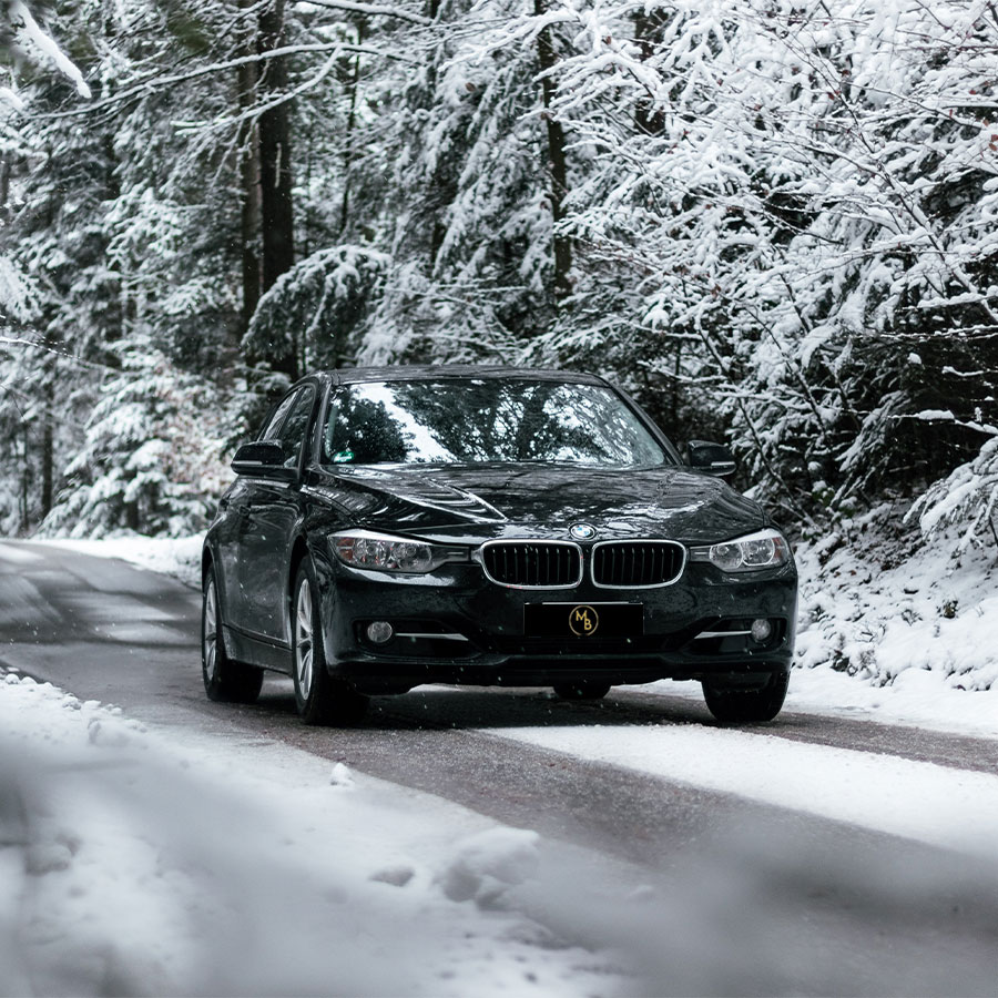 berline noire de chauffeur txi vtc sur une route enneigé